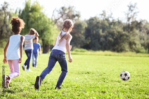 Cute little children playing football outdoors