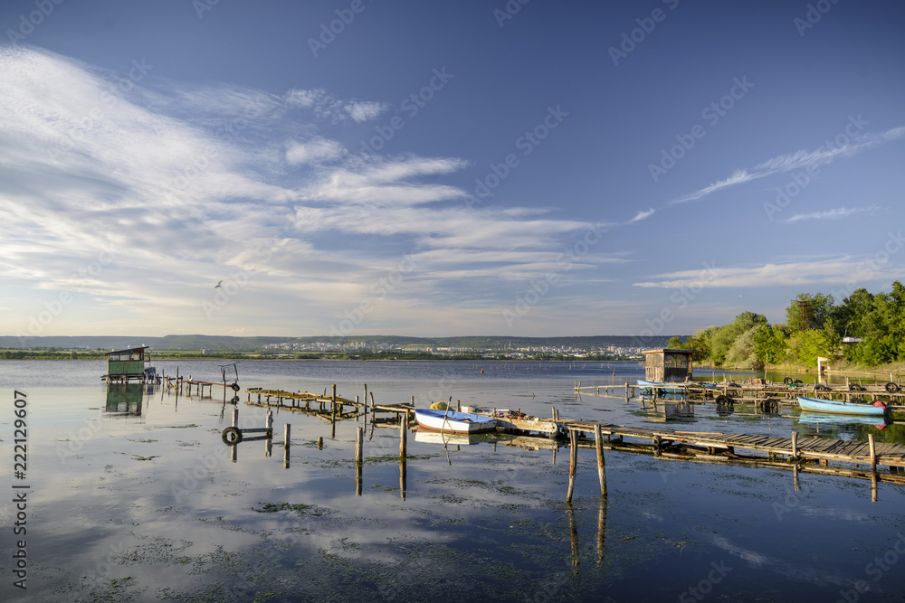 wooden pier on a lake with a fishing boat. sunset with calm water.