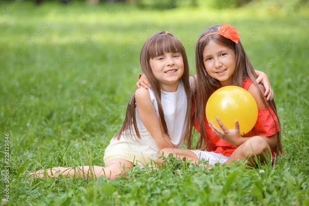 Cute little girls with ball in park on summer day Cute little girls with ball in park on summer day