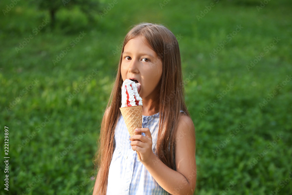 Cute little girl eating ice cream in park on summer day Cute little girl eating ice cream in park on summer day