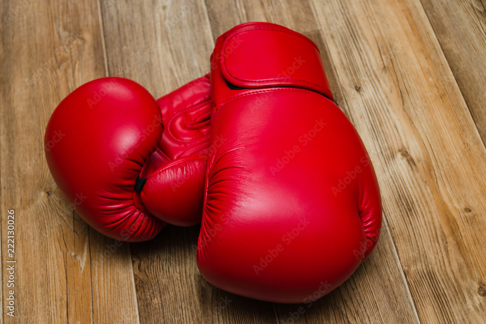 boxing gloves of red color on a wooden background, sports equipment