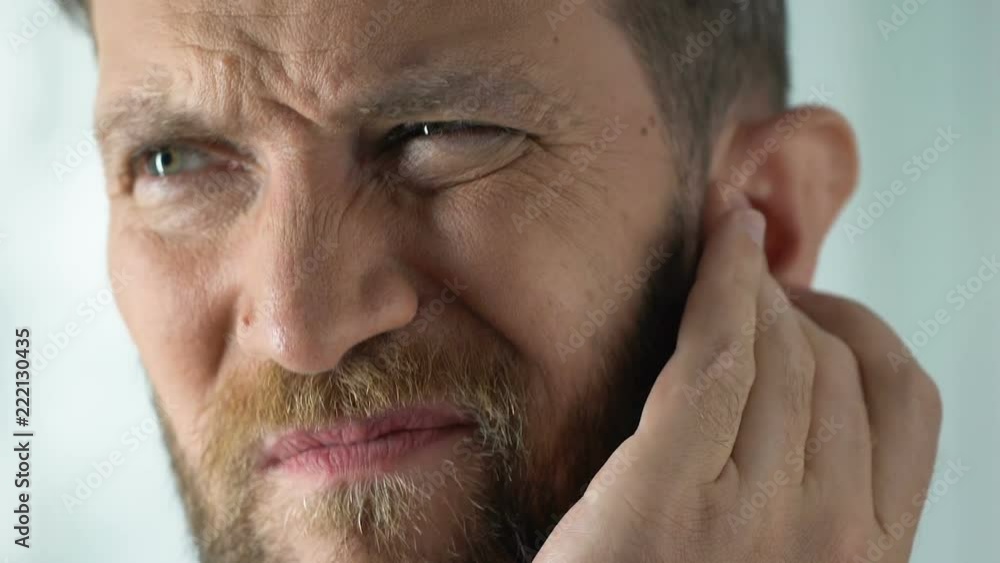 Man disturbed by painful stuffiness in ear infection or inflammation, healthcare Man disturbed by painful stuffiness in ear infection or inflammation, healthcare