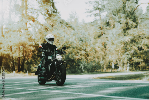 Biker In Helmet Is Riding On Highway In A Forest.
