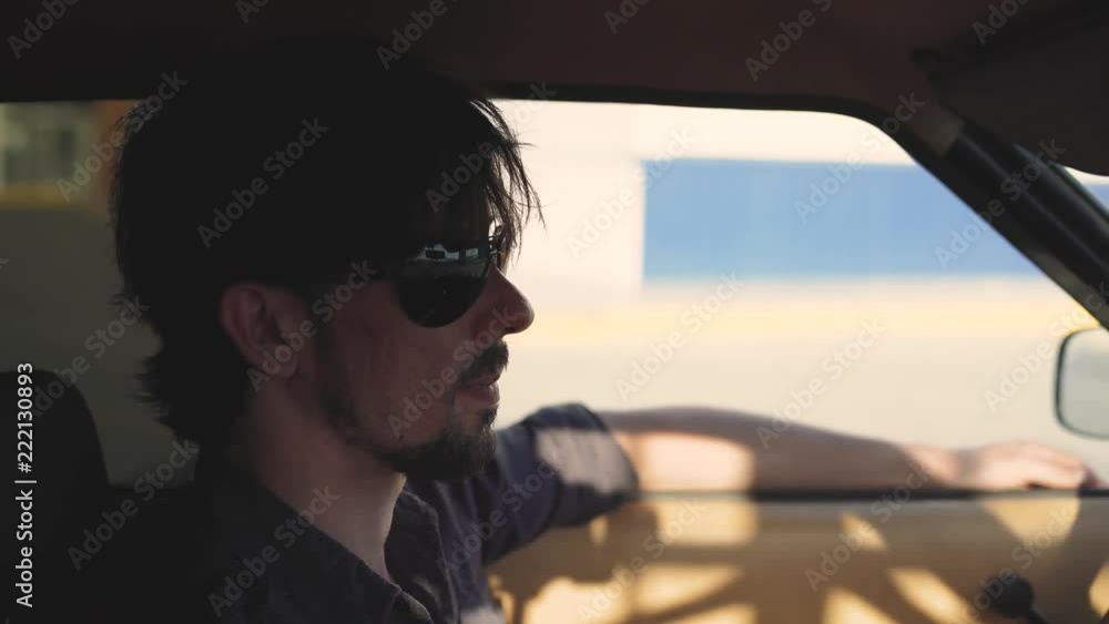 Portrait of handsome man in old classic powerful car on street, at sunset or sunrise Portrait of handsome man in old classic powerful car on street, at sunset or sunrise