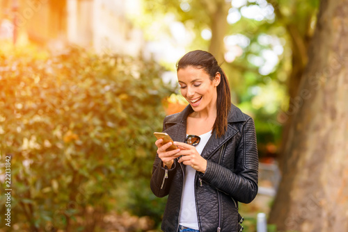 A happy young woman using her phone in a urban environment