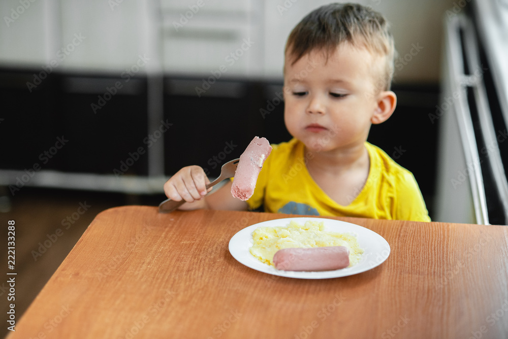 child in the kitchen eating sausage and mashed potatoes child in the kitchen eating sausage and mashed potatoes