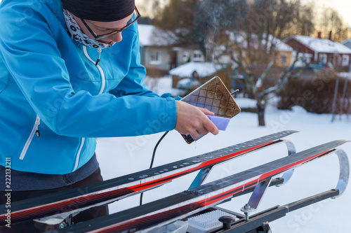 Woman waxing cross country skies, winter sport