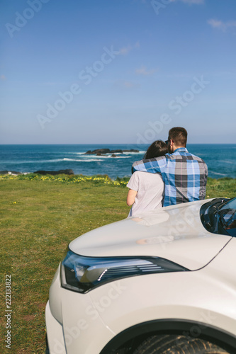 Young couple traveling by car making a stop and watching the landscape