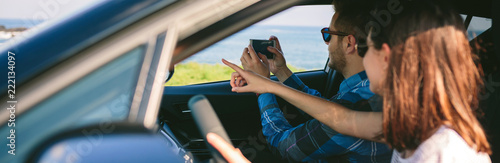 Couple traveling taking a picture of the landscape with the mobile from the car