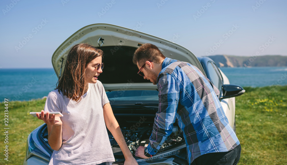 Young couple argue while trying to fix their broken down car