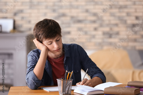 Tired teenager boy doing ho...