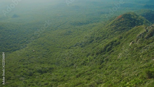 In this shot you can see brave man standing on steep cliff and throwing stone to the horizon. There you can see green jungle forest of Curacao island. photo