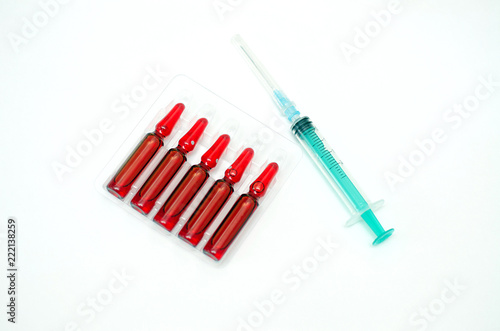 Syringe and ampoules with medicine of red color on a white background