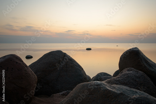 Large stones on the background of the sea at sunset tonted with orange. Soft focus. photo