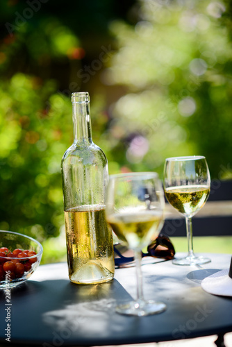 two glass of cool white wine with bottle outdoor in restaurant terrace during a sunny summer day