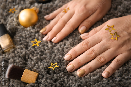 Hands of woman with festive manicure, Christmas decor and nail polishes on carpet, closeup