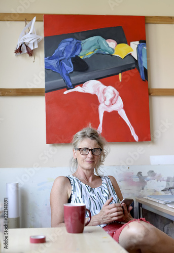 Female painter in her atelier, using smartphone photo