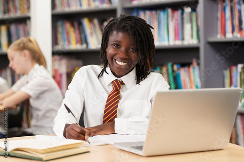 Obraz na plátně Portrait Of Female High School Student Wearing Uniform Working At Laptop In Libr