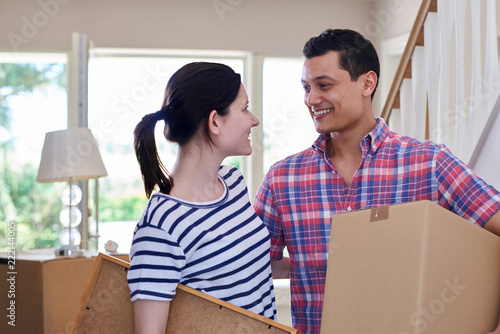Young Couple Carrying Boxes Into New Home On Moving Day