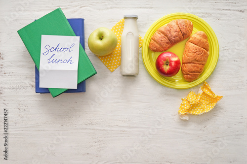 Sheet of paper with words SCHOOL LUNCH and appetizing food on white wooden table