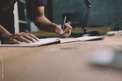 Checklist Writing Notice Remember Planning  assessment Concept,home office desk background,hand holding pen and writing note on wood table. photo