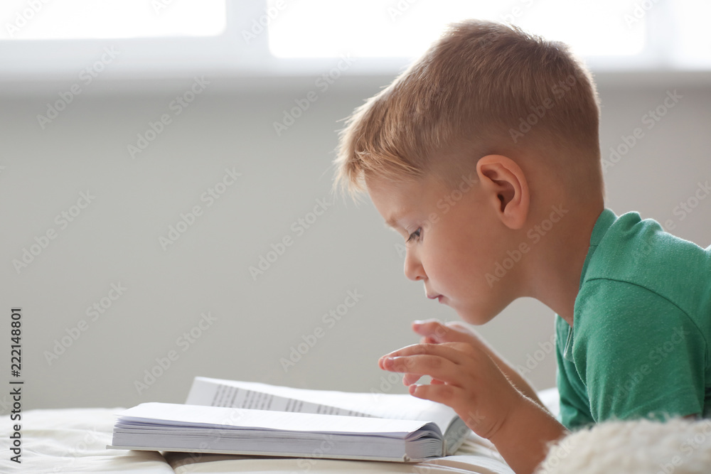 Cute little boy reading book on bed at home Cute little boy reading book on bed at home