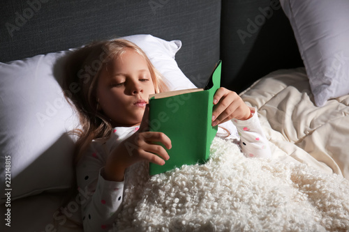 Young girl reading a green ...