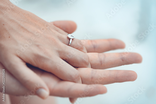 Engagement at the beach of tropical island. Close up of couple hands with silver ring on the finger.