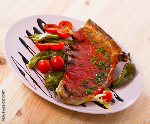 Spicy tomato sauce tasty lamb ribs served with peppers and cherry tomatoes