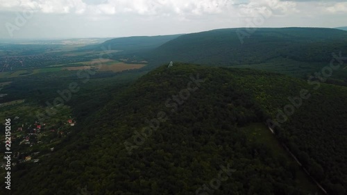 Drone orbiting around Watchtower on the top of greenish Gerecse Mountains in Hungary, view of the village in Tatab√°nya. photo