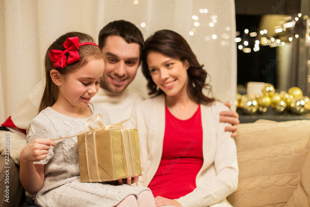 holidays, family and celebration concept - happy mother, father and little daughter with christmas present at home holidays, family and celebration concept - happy mother, father and little daughter with christmas present at home