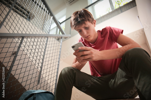 Sad teenage boy with mobile...