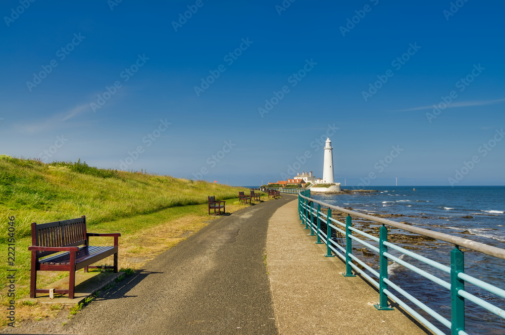 A promenade in Whitley bay with St Mary's lighthouse in the background.