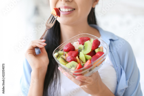 Woman eating healthy fruit salad at home, closeup