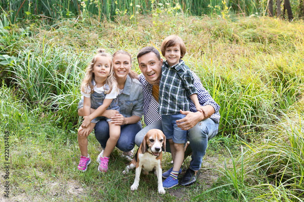 Obraz premium Happy family with cute dog resting in park