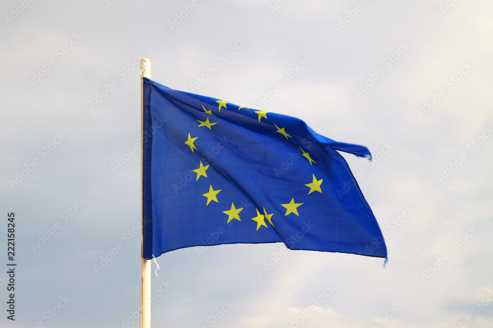 European Union flag on a blue sky with clouds background