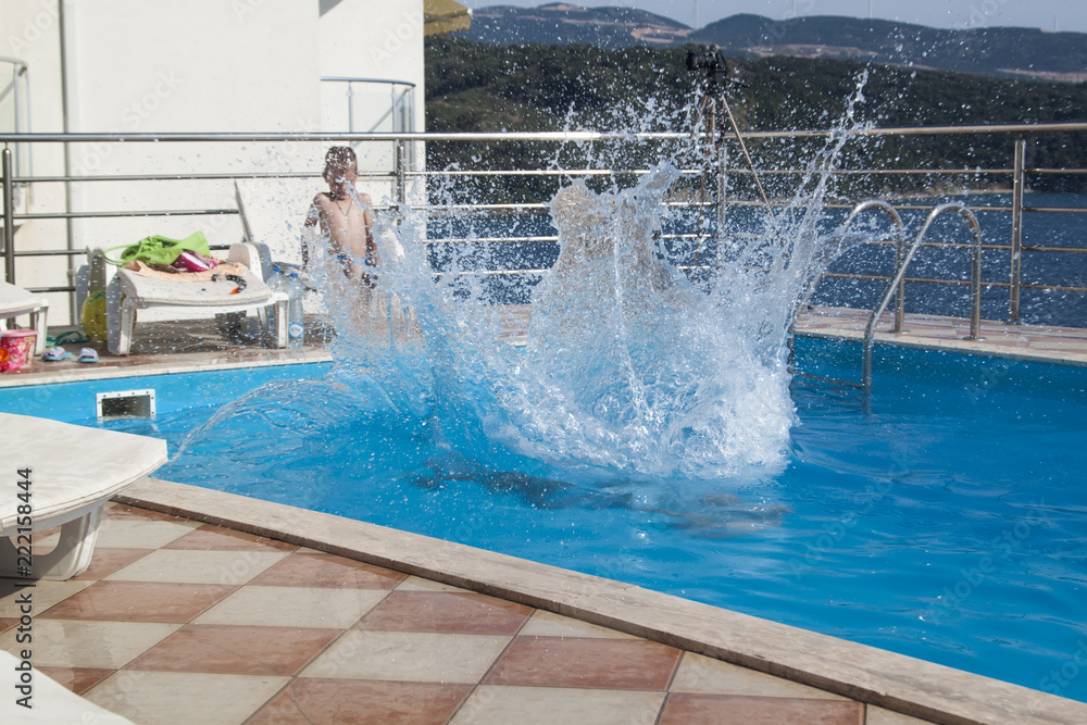 water splashes after the young man's jump into the pool