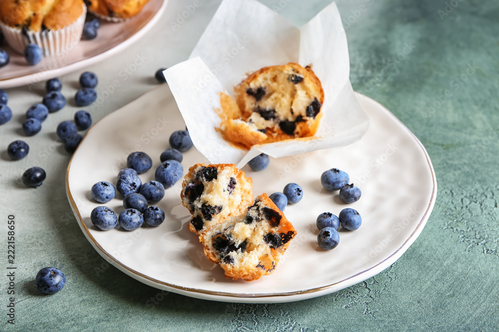 Plate with pieces of blueberry muffin on color table Plate with pieces of blueberry muffin on color table