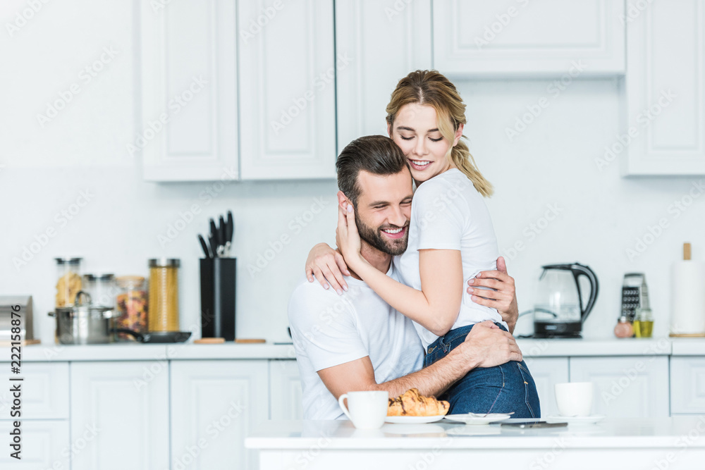 beautiful happy young couple in love hugging during breakfast in kitchen beautiful happy young couple in love hugging during breakfast in kitchen