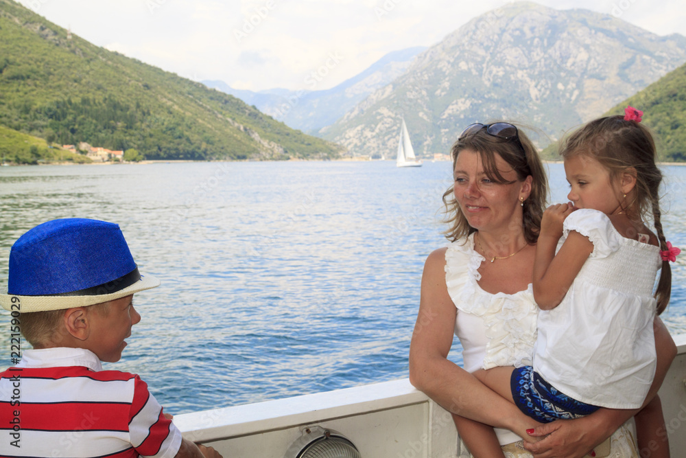 exciting journey with children. happy mother with her son and daughter in her arms cross the magnificent Bay of Kotor on the ferry