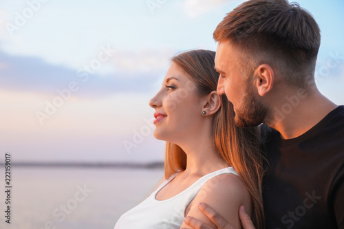 Happy loving couple near river at sunset