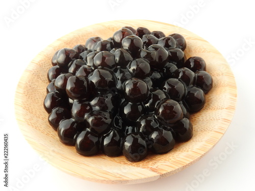 High angle view of tapioca ball (also known as boba in bubble tea) on wooden plate isolated on white background. Ingredients for making pearl milk tea and shaved ice at dessert shop. Food concept.