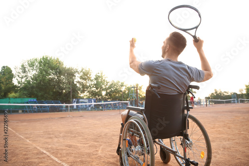 Young man in wheelchair playing tennis on court © Pixel-Shot