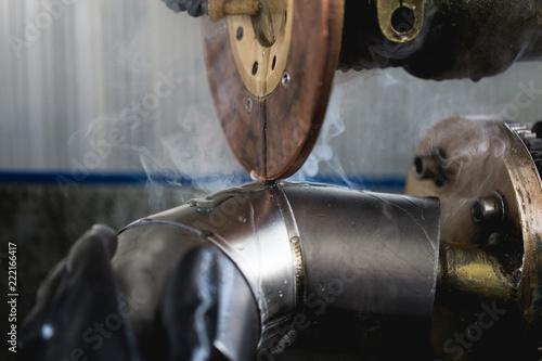 Metallurgy industry. Factory for production of heavy pellet stoves and boilers. Close up of manual worker welder on his job. Extremely dark conditions and visible noise.