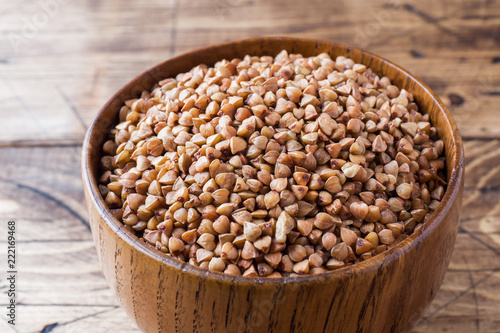 Buckwheat raw in a wooden bowl on a rustic wooden background.