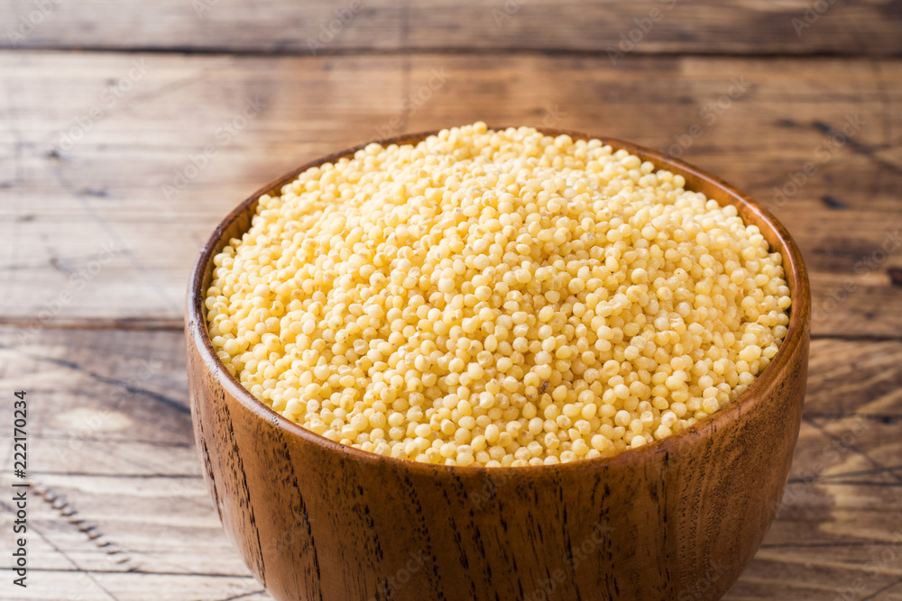 Grits millet raw in a wooden bowl on a rustic wooden background. Grits millet raw in a wooden bowl on a rustic wooden background.