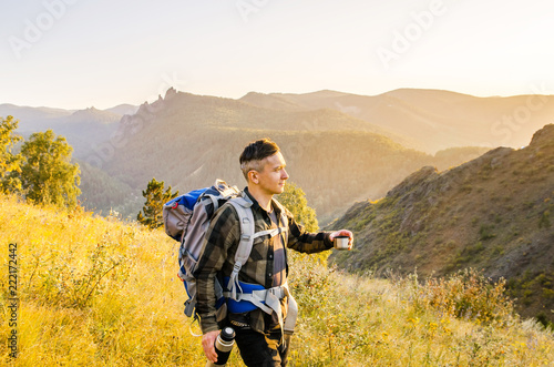 Young traveler with a thermos of tea on a mountain background.