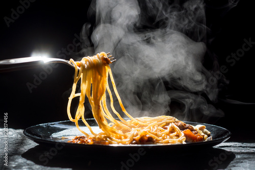 The steam from spaghetti with tomato sauce - homemade healthy italian pasta on dark background photo