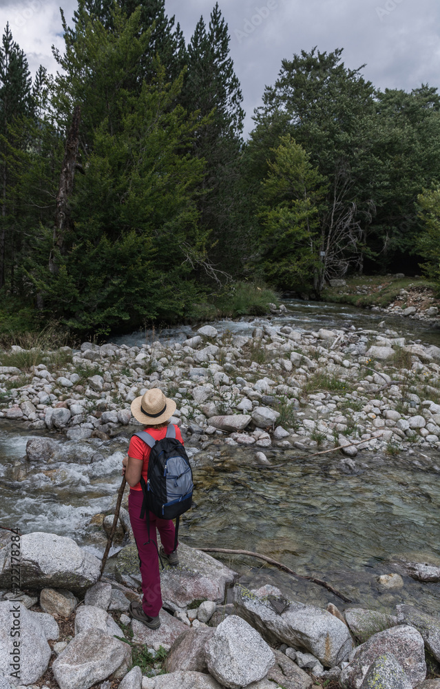 Woman hiking with a straw hat and backpack through the Spanish Pyrenees