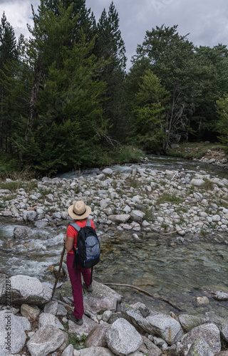 Woman hiking with a straw hat and backpack through the Spanish Pyrenees © expressiovisual